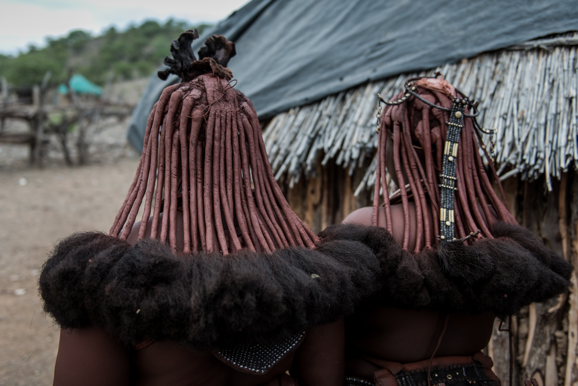 Typowe włosy kobiet Himba, pokryte mazią z tłuszczu, wraz z ozdobami